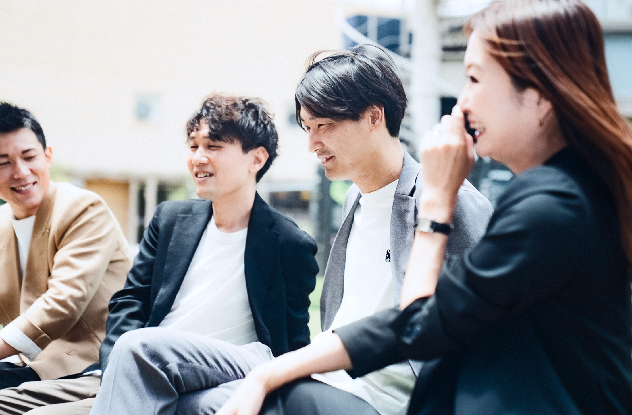 屋外で並んで微笑む4人の作業着姿の社員