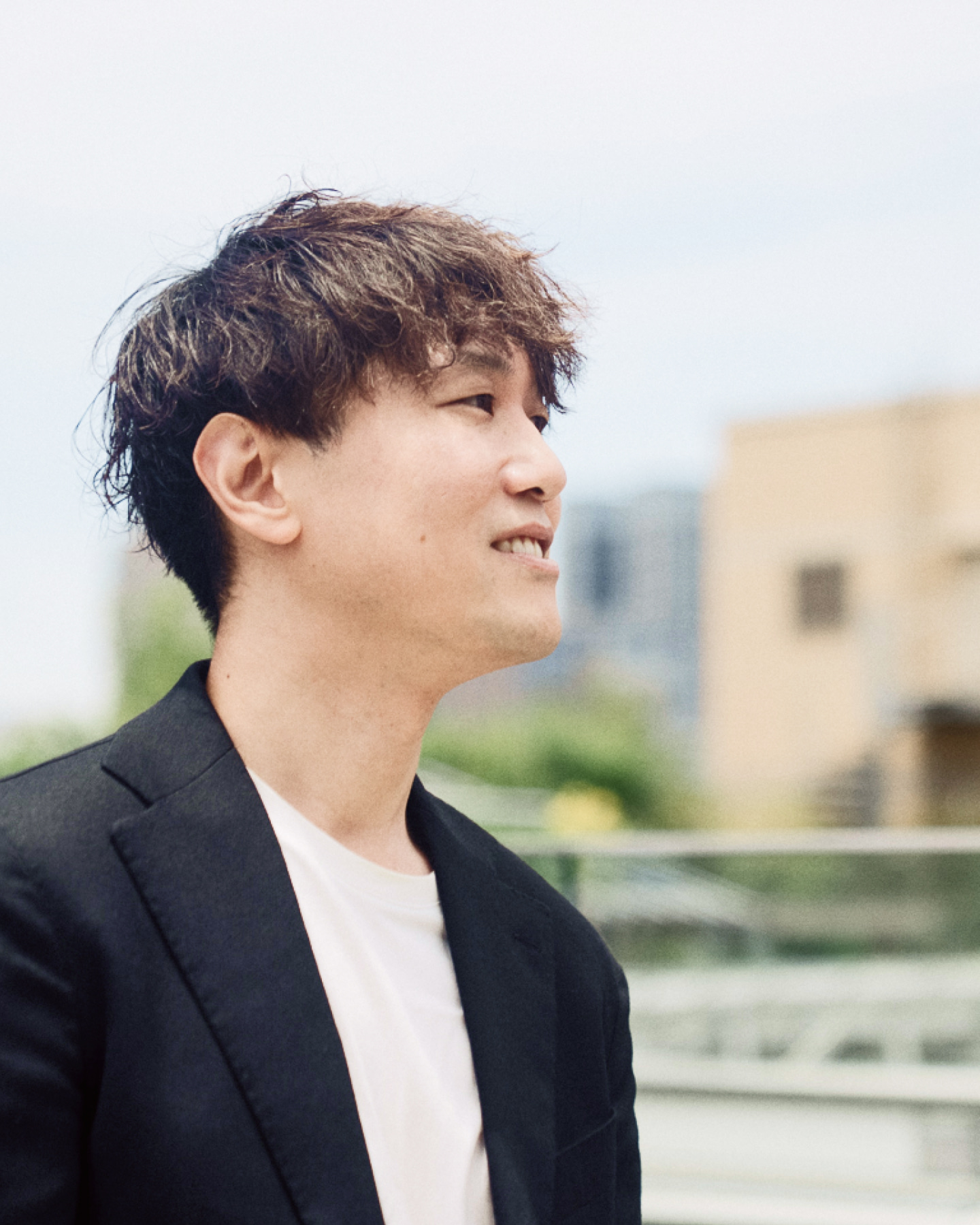 腕を組んで笑顔で立つ作業着姿の男性