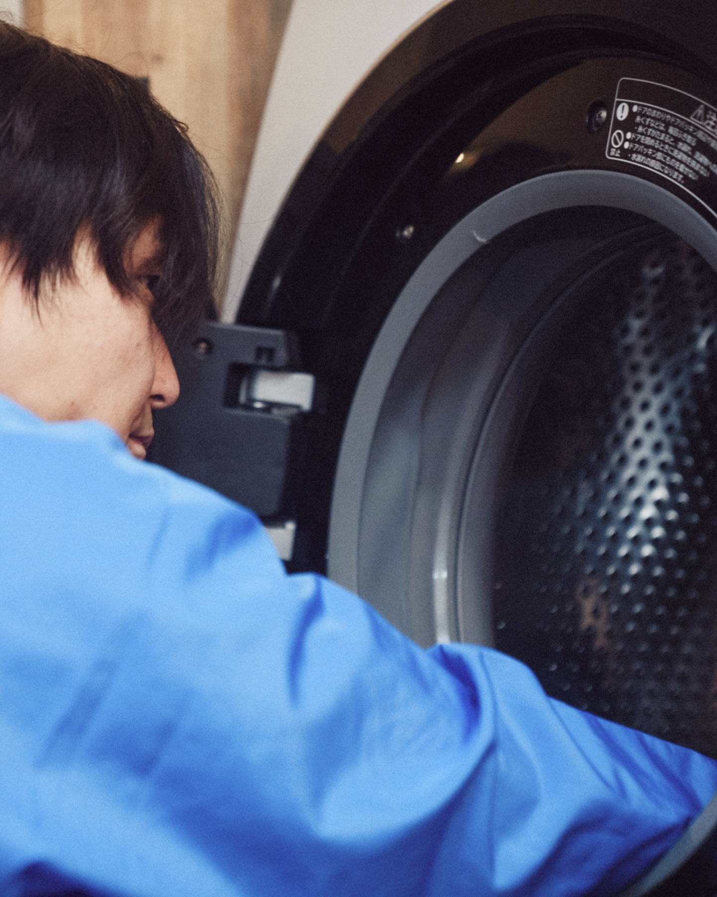 腕を組んで笑顔で立つ作業着姿の男性