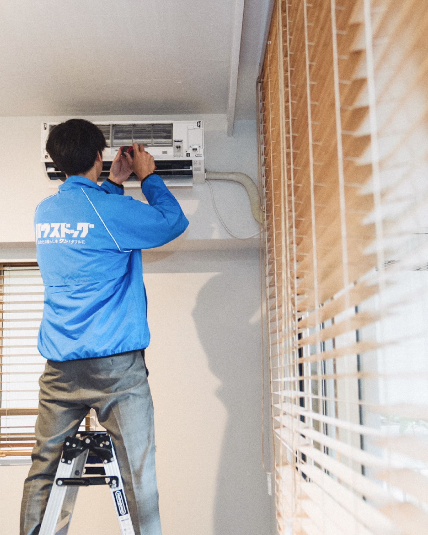 腕を組んで笑顔で立つ作業着姿の男性