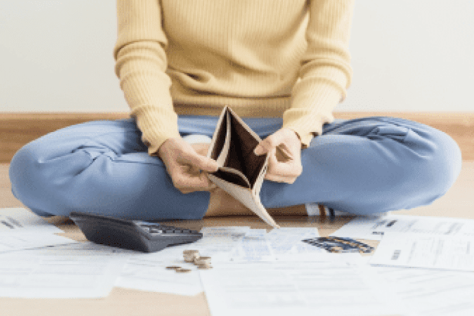 座って財布の中身を出し、お金の計算をしている人の写真